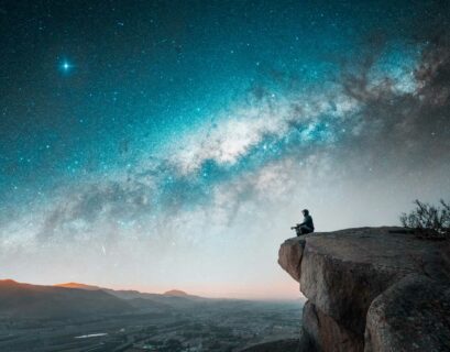 Mann sitzt auf einem Berg und meditiert unter dem nächtlichen Sternenhimmel