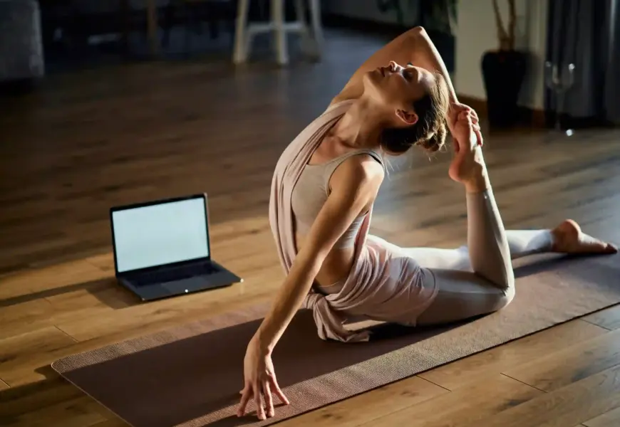 Frau macht Yoga auf dem Boden vor dem Laptop