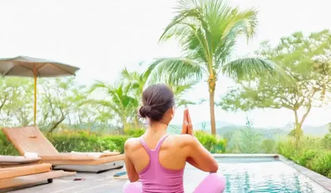 Frau macht yoga neben einem Pool im Garten