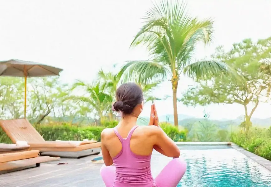 Frau macht yoga neben einem Pool im Garten
