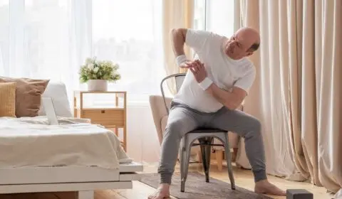 Mann macht Yoga auf seinem Stuhl zuhause