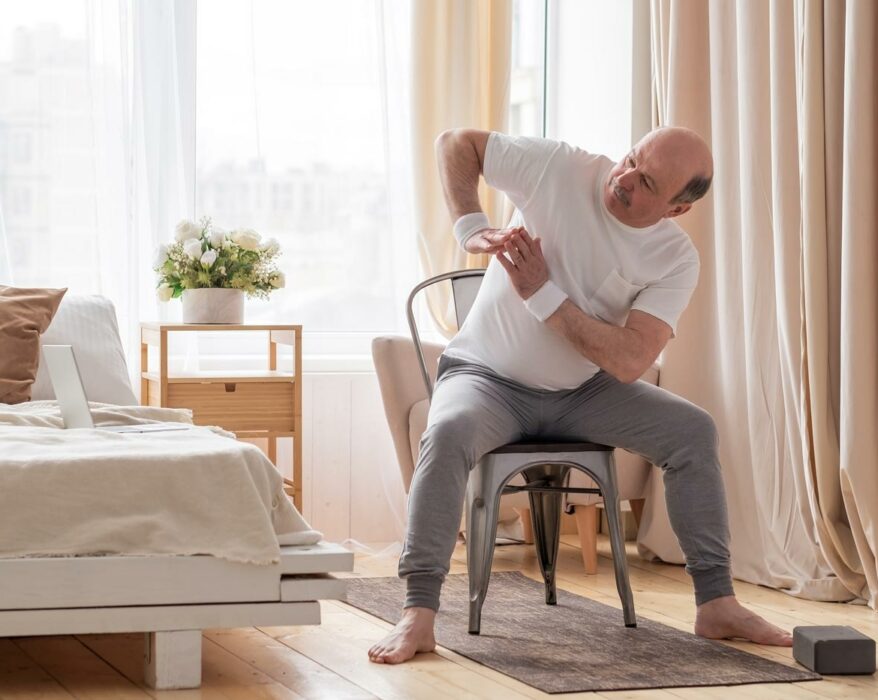 Mann macht Yoga auf seinem Stuhl zuhause