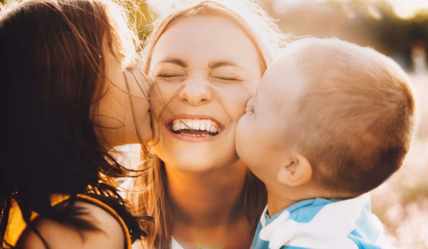 Zwei Kinder küssen ihre Mama auf Wangen am Muttertag