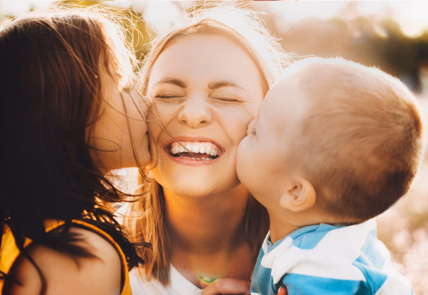 Zwei Kinder küssen ihre Mama auf Wangen am Muttertag