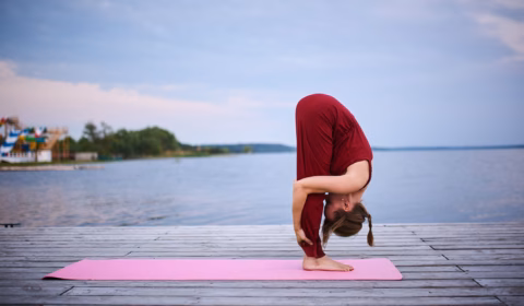 Frau macht eine Vorwärtsbeuge beim Yoga am Meer