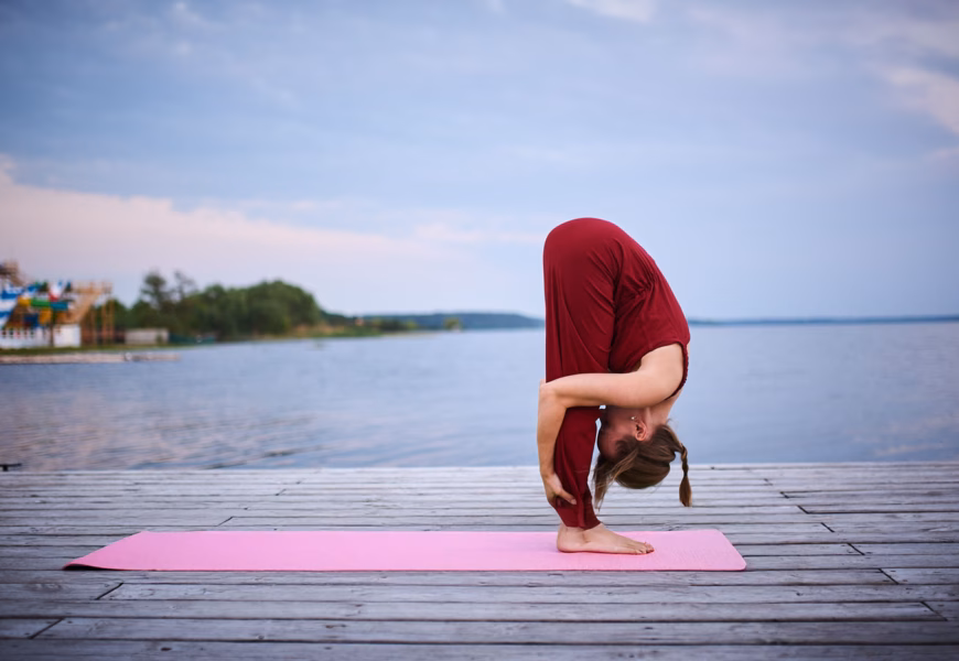Frau macht eine Vorwärtsbeuge beim Yoga am Meer