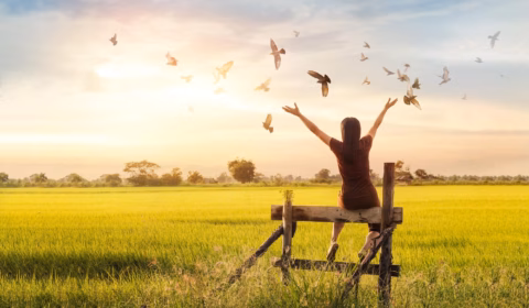 Betende Frau und freier Vogel im Einklang mit der Natur beim Sonnenuntergang