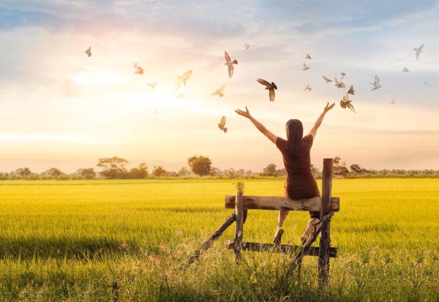 Betende Frau und freier Vogel im Einklang mit der Natur beim Sonnenuntergang
