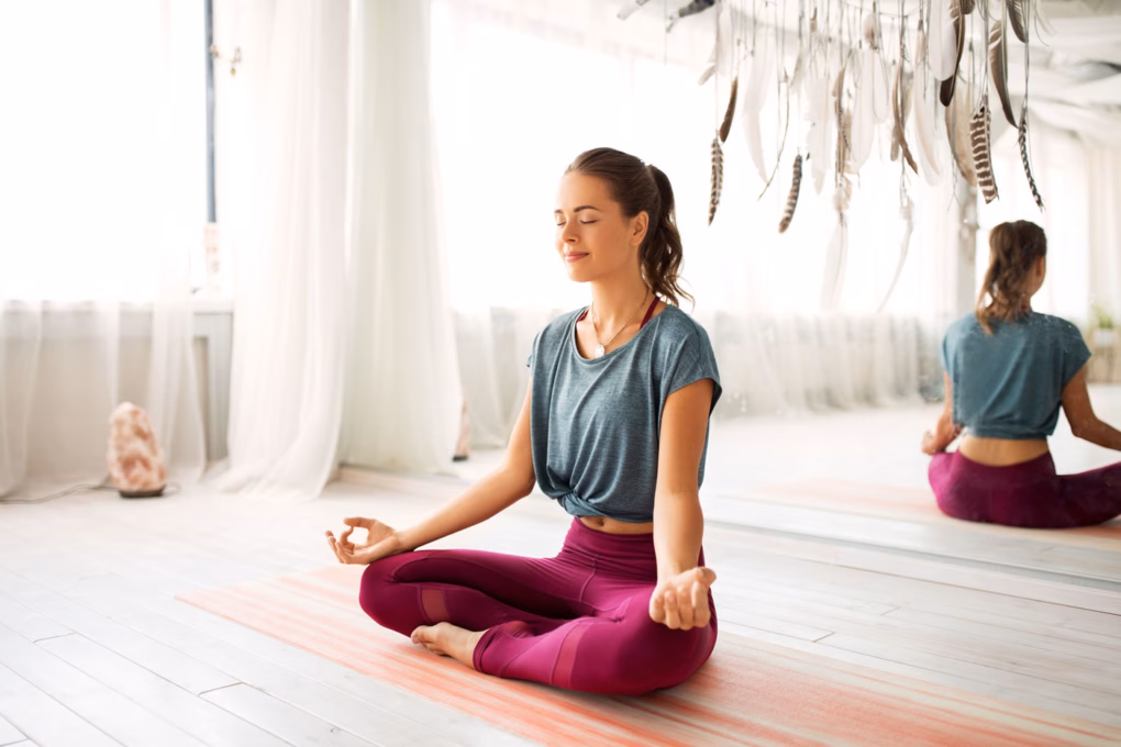 Frau sitzt im Meditationssitz auf dem Boden und meditiert