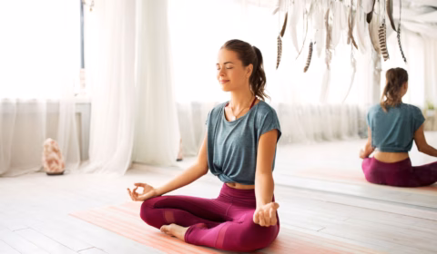 Frau sitzt im Meditationssitz auf dem Boden und meditiert