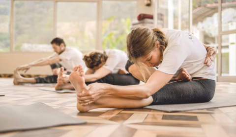 Drei Personen machen Yoga auf dem Boden