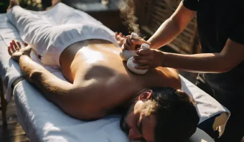 Mann bekommt eine Rückenmassage mit Kräuterstempeln
