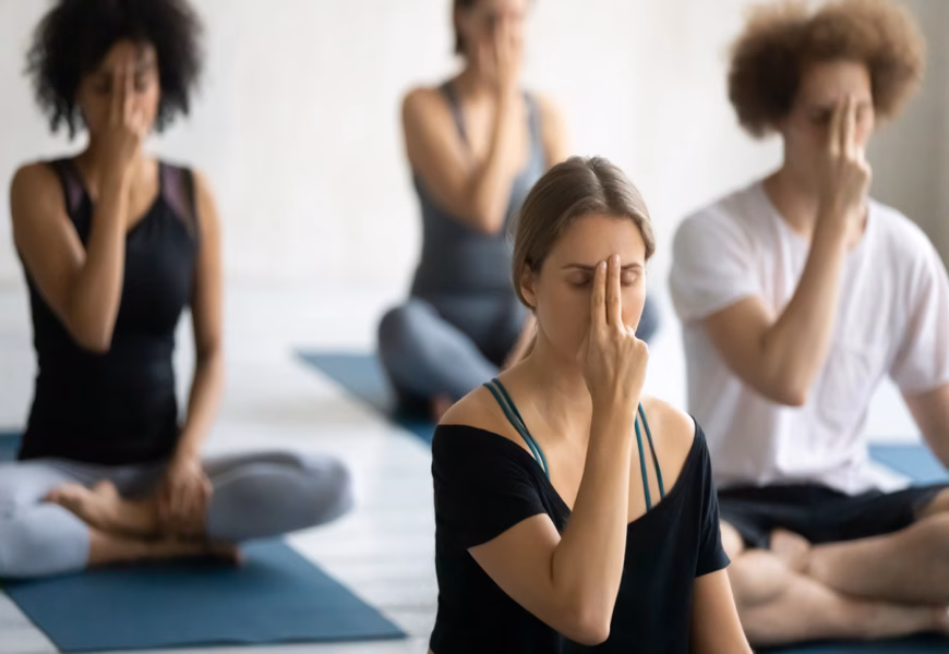 Vier Personen machen eine Meditation und halten sich mit zwei Finger das dritte Auge