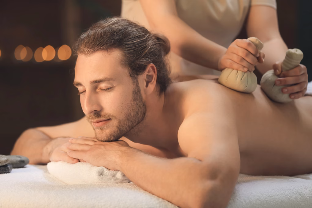 Mann bekommt eine Kräuterstempel Massage in seiner Kur für Männer