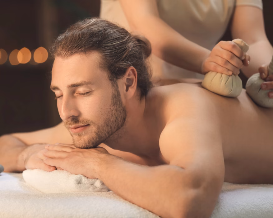 Mann bekommt eine Kräuterstempel Massage in seiner Kur für Männer
