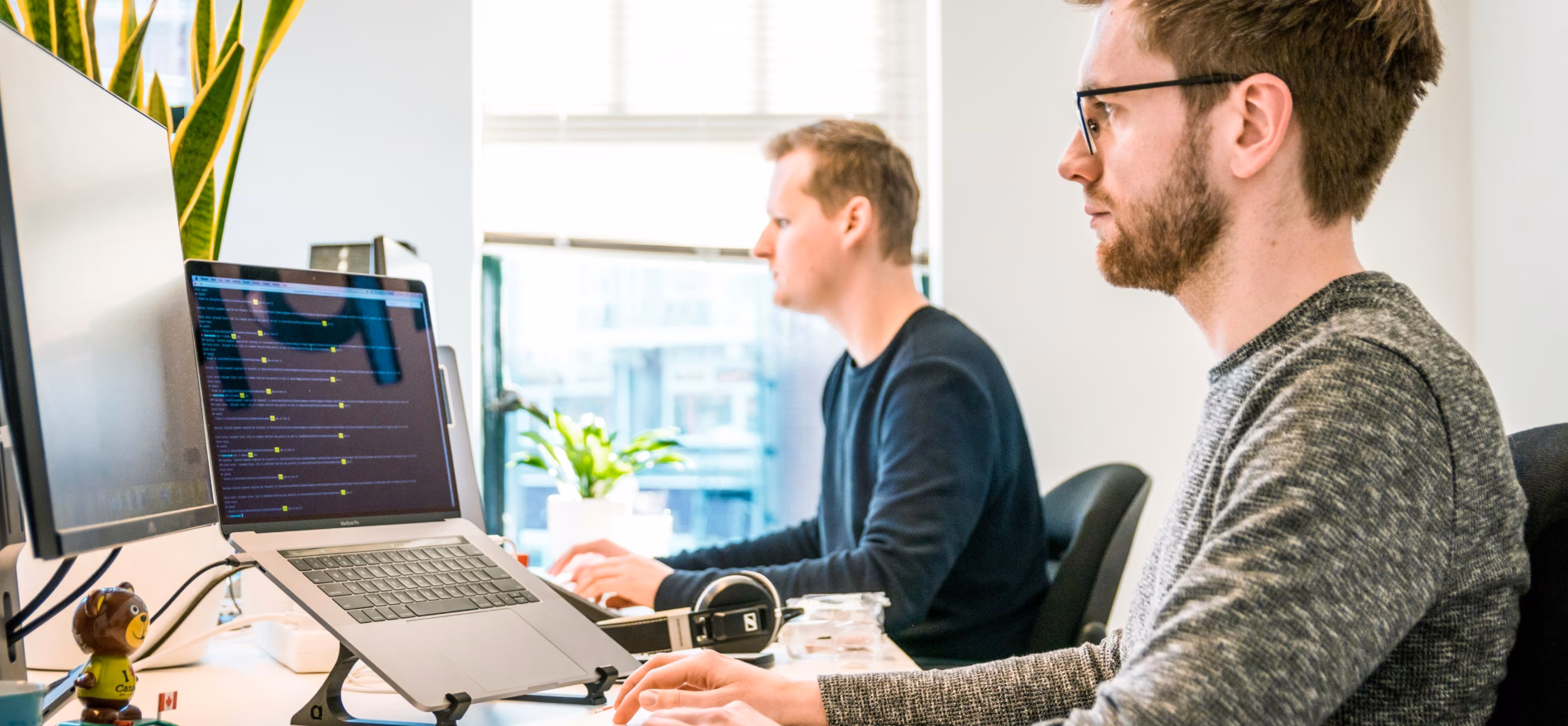 man sitting on chair wearing gray crew-neck long-sleeved shirt using Apple Magic Keyboard