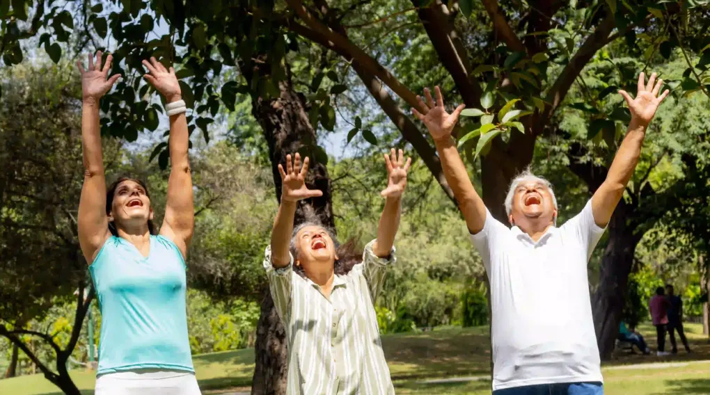 Drei Leute machen in der Natur Lachyoga