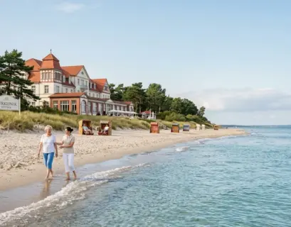Patienten beim entspannten Spaziergang am Strand vor einer Kurklinik an der Ostsee